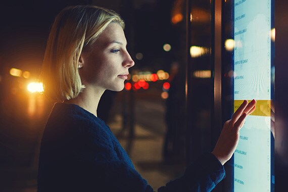 Woman outside in the dark using brightly lit interactive digital menu
